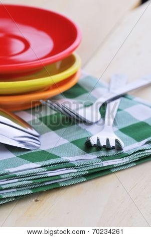 Close-up Of Stainless Fork And Spoon On Tablecloth With Red,yellow, Orange Plate.