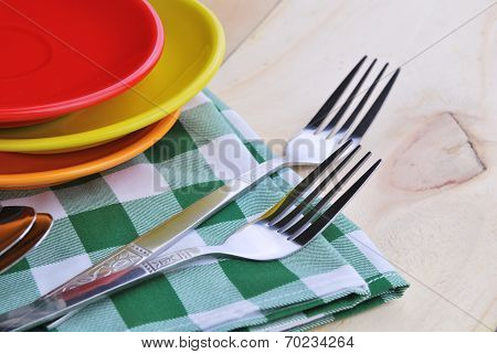 Close-up Of Stainless Fork And Spoon On Tablecloth With Red,yellow, Orange Plate.
