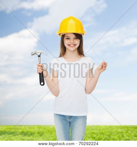 childhood, construction, architecture, building and people concept - smiling little girl in protective helmet with hammer