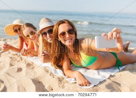 summer vacation, travel, technology and people concept - group of smiling women in sunglasses making selfie with smartphone on beach