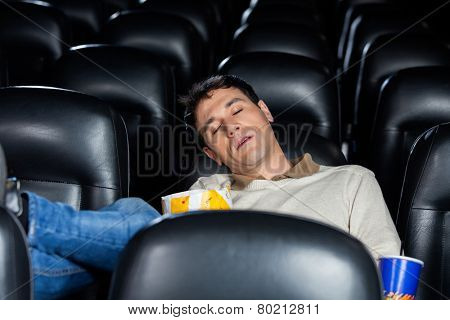 Bored mid adult man sleeping at cinema theater