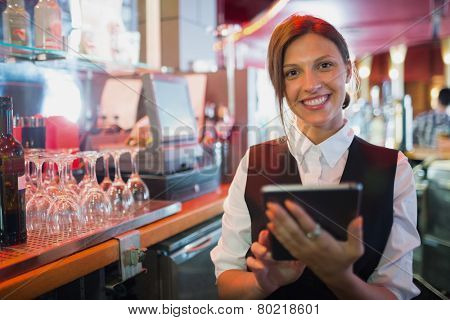Focused barmaid using touchscreen till in a bar