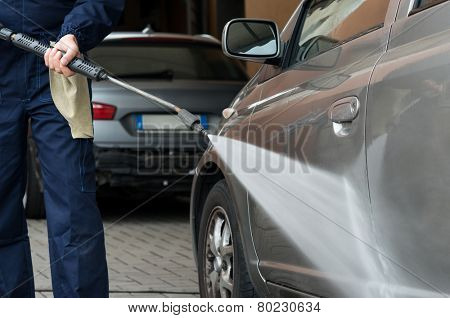 Closeup Of A Mechanic Washing A Car By Pressured Water At Garage