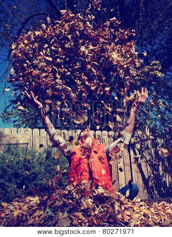 a man playing in autumn leaves toned with a retro vintage instagram filter effect