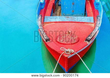 Empty Red Wooden Boat With Blue Broadside Moored In Port With Silent Azure Water