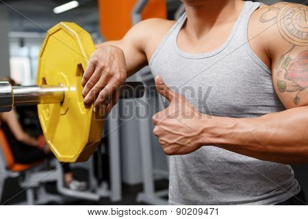 Weightlifter leaning on barbell in gym
