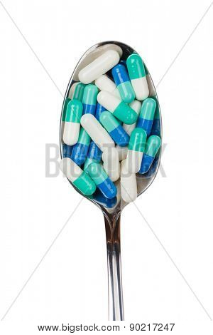 Green pilules in the spoon, isolated. Healthcare concept.