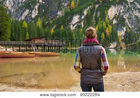 Woman Hiker Looking Out At Wooden Boats And Pier On Lake Bries
