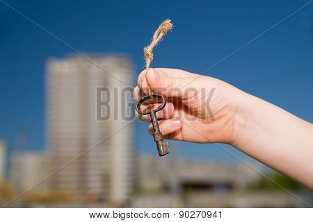 Child Hand Holding An Old Key To The House Against The Sky