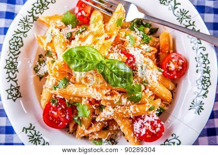 Plate with pasta pene Bolognese sauce cherry tomatoes parsley top and basil leaves