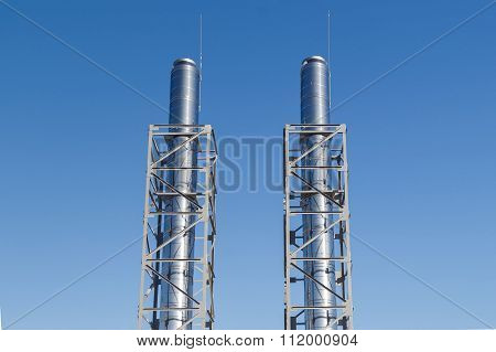 Two metal chimneys blue dots over bright sky