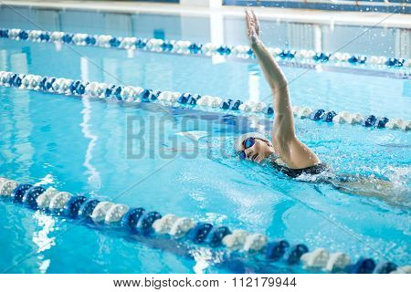 Young girl in goggles swimming front crawl stroke style