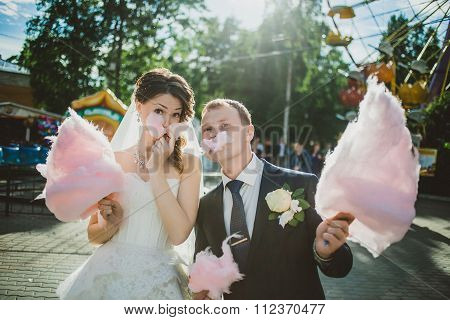 newlywed happy couple walking in the amusement park with cotton candy