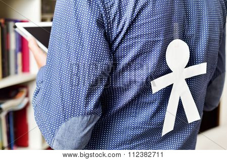 young man with a paper man in his back with for the dia de los inocentes, the innocents day, a feast held in spain, hispanic america and philippines equivalent to april fools day
