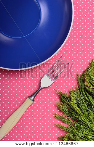 Empty blue plate with a fork on a red background with polka dots fennel