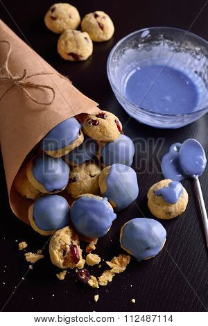 Cottage Cheese Cookies With Cranberries In A Blue Glaze And In Kraft Bag On A Dark Background