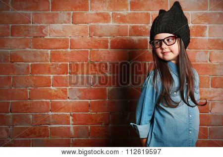 Portrait of little fashion kid girl on bricks wall background