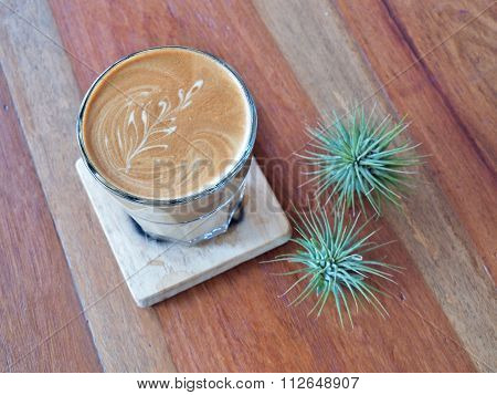 Latte art coffee on the wood saucer.