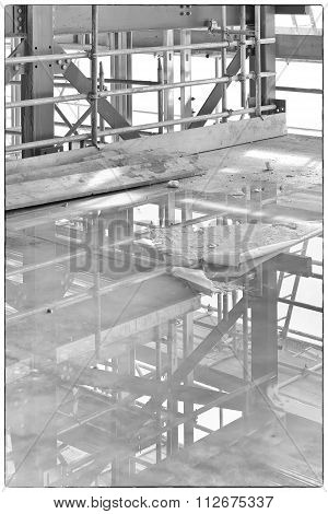 A Construction Site With Concrete Slab With Water Puddle And Scaffolding