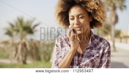 Beautiful african-american woman wearing plaid shirt talking on cell phone in the park