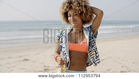 Young woman holding bottle against sand beach and seashore