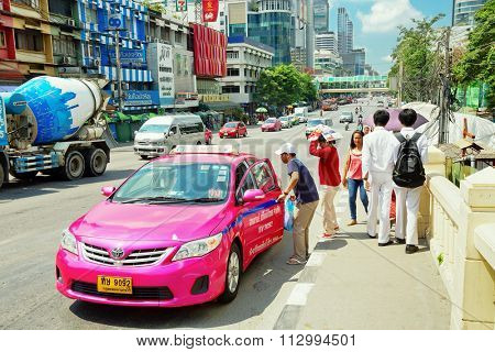 BANGKOK, THAILAND - APRIL 29, 2015: Pedestrians stopped a taxi in Bangkok. There are 150,000 taxis in Bangkok. All are metered with the starting fee of 35 Baht for the first 3 kilometers.