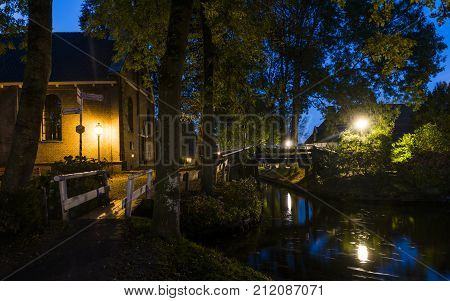 Autumn evening in the small village of Giethoorn in Overijssel Netherlands with lantern at the church bridges and canals.