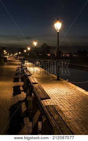 Evening in the small village of Giethoorn in Overijssel Netherlands with lanterns and benches at the harbor.