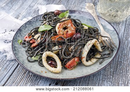 Italian linguine con tinta de calamari and prawns with olives as close-up on a plate