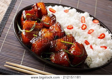 Delicious Spicy Caramel Pork Belly With Rice Close-up On A Plate On A Table. Horizontal