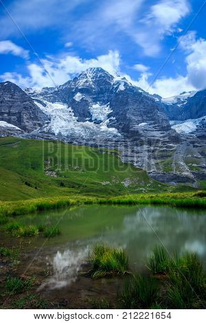 Mountain Monch (4.107m - 13.474ft) and Jungfraujoch + reflection in water in the Bernese Alps in Summer. Kleine Scheidegg Bernese Oberland Switzerland.