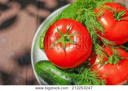 Fresh tomato and cucumbers on wooden table. Stock photo.