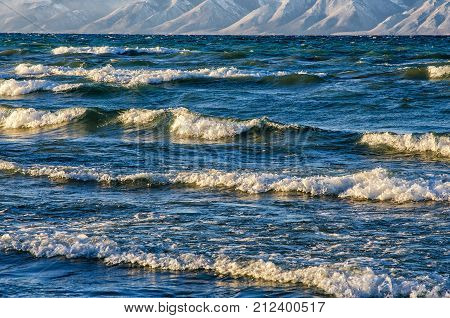 frozen sea view with mountans. Waves hitting icy coastline