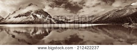 Bow Lake panorama reflection with snow capped mountain and forest in Banff National Park