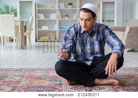 Young muslim man praying at home