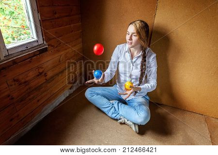 beautiful young smiling woman sitting and juggling