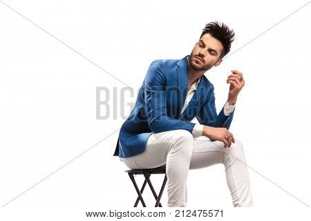 seated elegant man looks back over his shoulder on white background