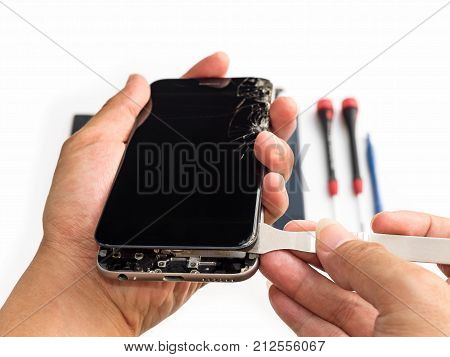 Close-up of technician hand taking off cracked smartphone screen on blurred smartphone component background