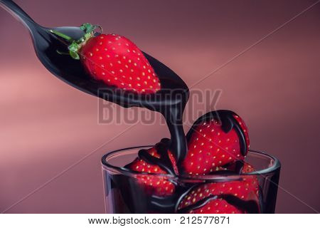 The strawberry in a glass watered with chocolate