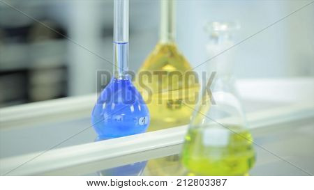 laboratory glassware with color liquid and with reflection. test tubes and flasks with green and blue liquid in a laboratory. Green and blue flask in laboratory. Fluid in laboratory flasks. Scientific biochemical laboratory. Red, blue, green, yellow liqui