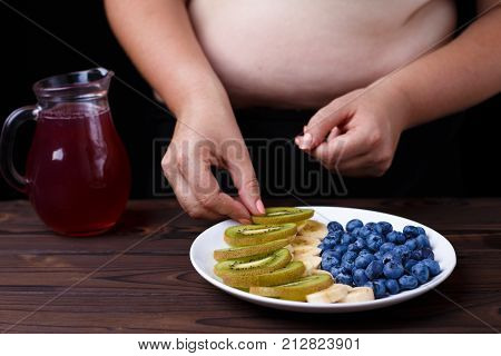 Overweight Fat Woman Taking Kiwi Slice From Fruit Plate. Juicy Tasty Low-calorie Dessert For Weight