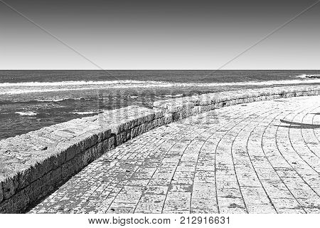 Promenade along the Mediterranean Sea in Akko. Embankment and city beach of old arabic city Akko located north of Israel. Black and white picture