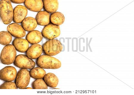 A lot of dirty potatoes on a white background. Potatoes scattered on the left side.