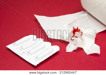 A photo of rectal candles, used shits of bloody toilet paper and a toilet paper roll. Blood drops, traces. Hemorrhoids, constipation treatment health problems. Menstrual, hemorrhoids bleeding