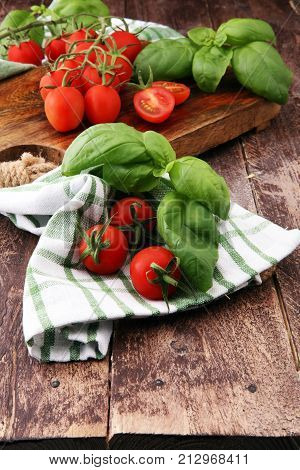Cherry tomatoes with basil and dish towl on cutting board.