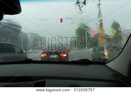 Driving Car In The Rain On Wet Road. Rainy Weather Through The Car Window. Rain Through Wind-screen 