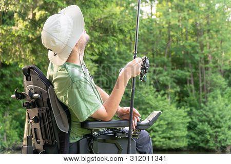 Happy Man In A Electric Wheelchair Throwing Fishing Pole At The Beautiful Pond In Natue On A Sunny D