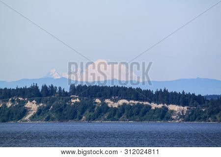 The Snow Capped Mountain Of Mt. Rainer In Washington From The Water.