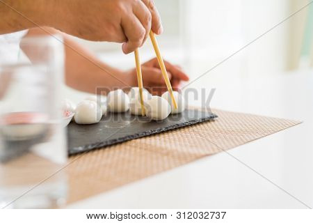 Middle age man eating asian dim sum using chopsticks at home