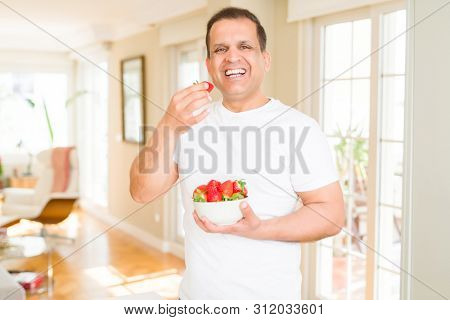 Middle age man eating straweberry at home
